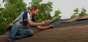 A man working on replacing shingles on a roof