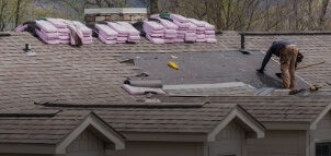 A person works on repairing a roof