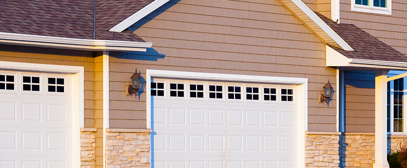 exterior of a custom built garage; white doors with brown siding on the home