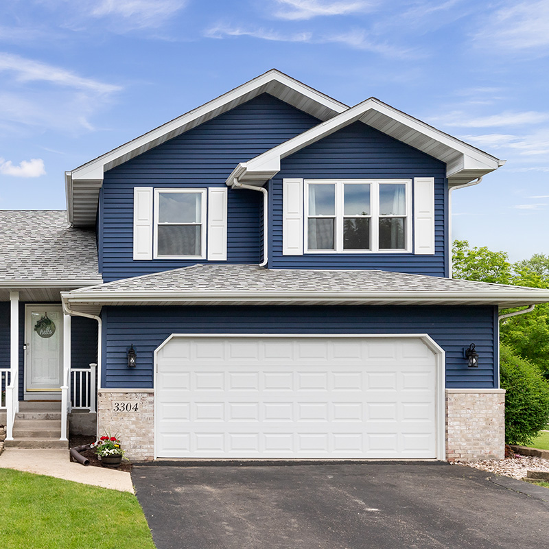 Image of the exterior of a blue home with a large, white garage 