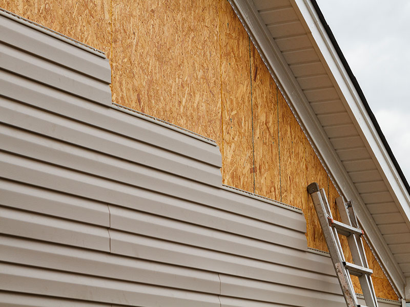 a house is getting new, tope-colored siding