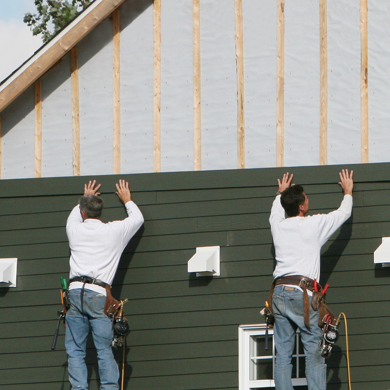a siding contractor works on replacing the siding of a home